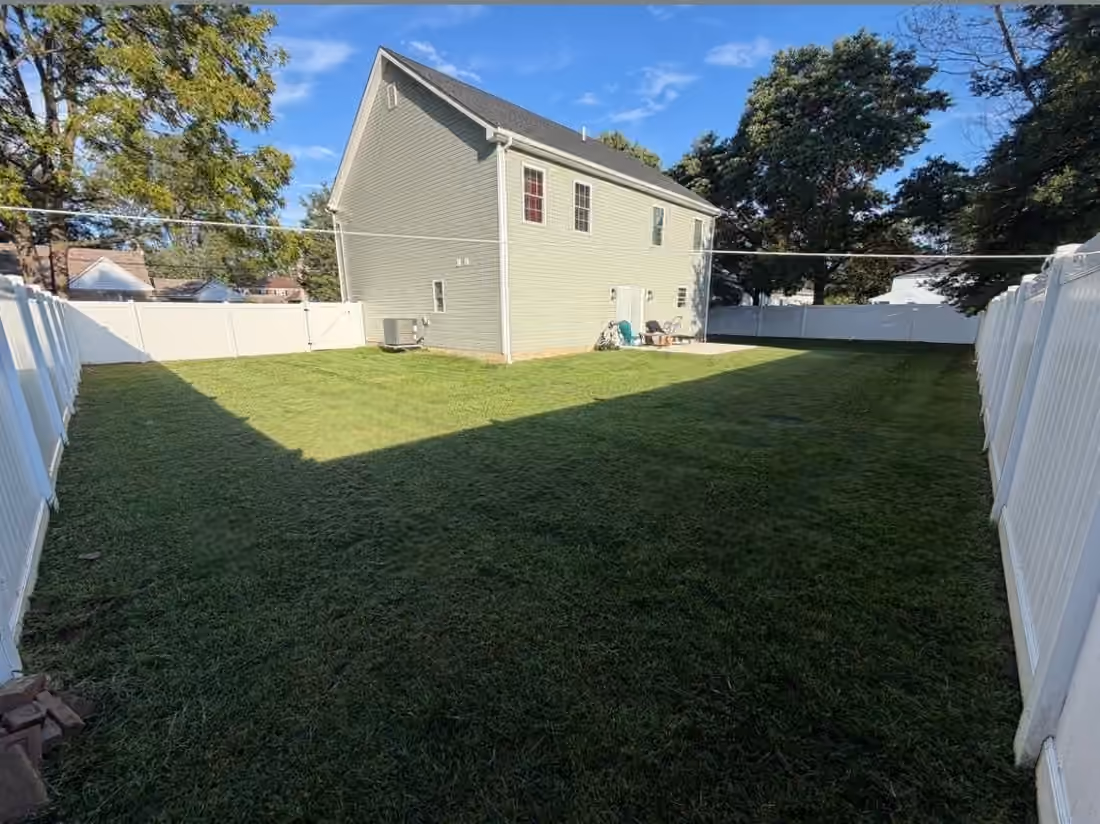 Mowed fenced lawn wrapping around the back of a house