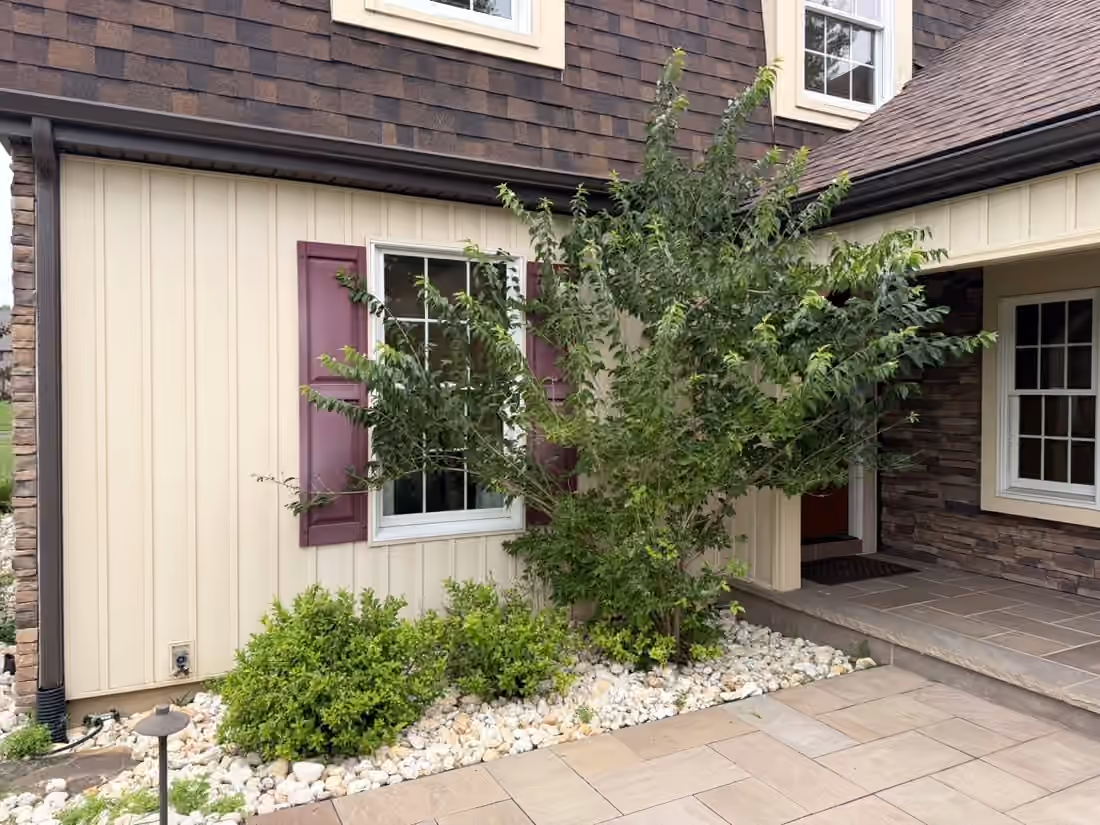 Shrubs and river rock beside the front entry and paver walk